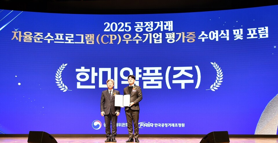 オンラインカジノ最新コンプライアンスチーム長のユ・スンヒョンさん(写真右)が、ナム・ドンイル公正取引委員会副委員長からCP評価証明書を受け取り、記念写真を撮っている。 (出典：オンラインカジノ最新)